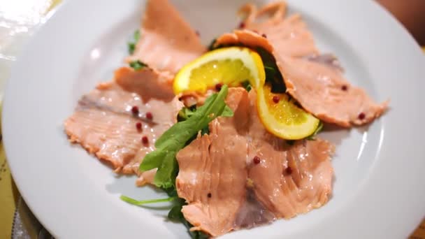 Säsongsbetonade skivor av lyx röd lax fisk på vit tallrik, medelhavsskaldjur delikatess i restaurang. Rökta laxskivor med peppar, raketsallad och citronskivor. Medelhavsrestaurang — Stockvideo