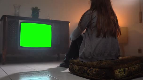 Starý obývací pokoj s tmavým osvětlením a zelenou obrazovkou blikající vintage TV, zadní pohled na ženu sedící před retro televizí a sledující mediální zprávy a vysílání. Retro atmosféra v bydlení — Stock video
