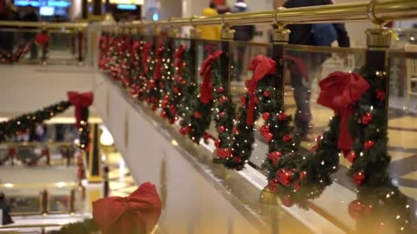 ローマ,イタリア- 2019年12月19日:クリスマスツリーの枝、輝くガーランド、赤いリボン、ボールで美しく装飾されたローマのショッピングモール、ショッピングセンター内を歩く人々、やって — ストック動画