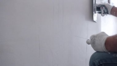 İnşaat alanındaki eski harabe duvarı yeniden inşa eden işçiler, beton duvarı metal spatulayla yıkıp beyaz macun kaplaması ve silen inşaatçılar. Evdeki duvarları sıva yapan tamirci, duvarları hizalayan.