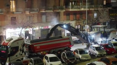 ROME, ITALY - 9 Nisan 2021: not makinesi ve çöp kamyonu gece yolda çalışıyor, not öğütücü yol çizgisi, asfalt sıkma ve kamyona atma. Gece yolu inşaatta çalışır.