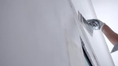İnşaat alanındaki yeniden inşa edilmiş duvarları çürütme işlemi, beton duvar yüzeyini metal spatula kullanarak beyaz macunla hizalayan işçiler. Apartman ya da evin onarım işleri bitiriliyor