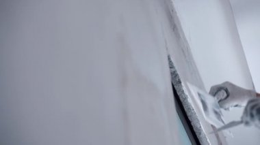Eski apartman veya evde duvarların yeniden inşası, metal spatula kullanarak duvar yüzeyini beyaz macunla hizalayan endüstriyel işçiler. Beyazlatıcılıktan önce beton duvarı yıkma işlemi. Onarılıyor