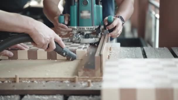 Equipo de carpintería en la fábrica del taller que fabrica muebles y productos de madera, carpintero tallado diseño de tablero de madera con máquina de pulir, mientras que otro trabajador limpieza aserrín con aspiradora — Vídeo de stock