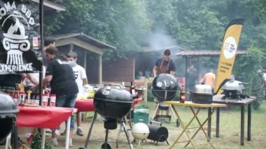 ROME, ITALY - 6 Haziran 2021: Arkadaşlar Roma eteklerinde geleneksel barbekü pikniği düzenlediler, insanlar barbekü ızgarasında et çeşitlerini baharat ve otlarla kızartıyorlar. Barbekü piknik partisi