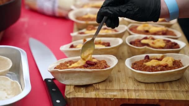 Persiapan makanan ringan tradisional Italia untuk pesta barbekyu, koki dalam sarung tangan mengisi pastri dengan saus tomat dengan mince dan menuangkan saus pedas kuning di atasnya. Pelayanan katering tradisional — Stok Video