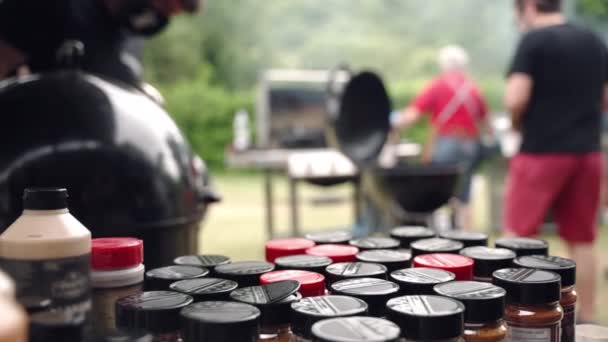 Colección de diferentes tipos de especias para cocinar alimentos, botellas de especias para asar carne y verduras en rejilla de barbacoa. Organización de fin de semana barbacoa picnic fiesta al aire libre con fumadores barbacoa — Vídeo de stock