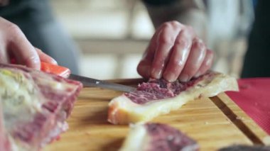 Tahtada kurutulmuş sığır filetosu, yemek servisi için kurutulmuş bifteği dilimlemek için keskin bıçak kullanan kasap. Lüks restoranlar için tütsülenmiş et bifteği, biltong et üretimi