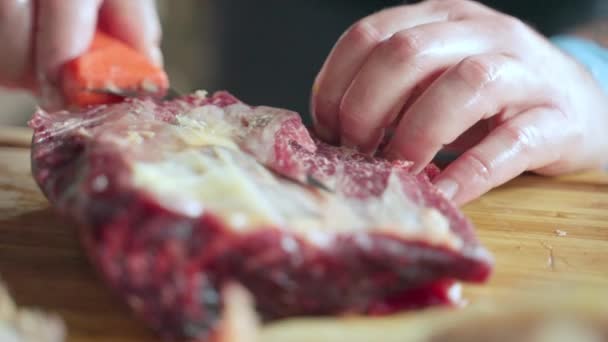 Homem sem luvas descascando carne seca na tábua de madeira, profissional açougueiro cortando casca de biltong com faca afiada. Fabricação de carne seca em talho, produção de carne de porco seca — Vídeo de Stock