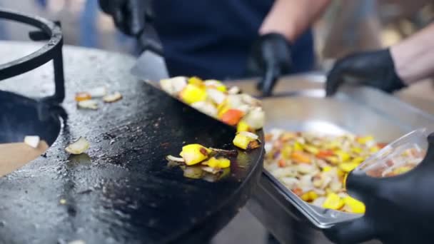 Festa de piquenique tradicional, homem de luvas pretas usando pinças de cozinha para colocar legumes grelhados prontos dentro do recipiente de papel alumínio. Vegetais grelhados saudáveis como cebola, pimentão e — Vídeo de Stock