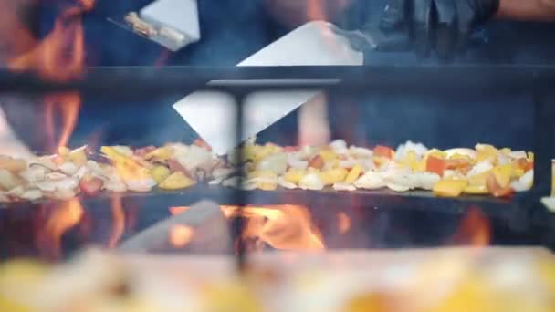 Straat voedsel koken op professionele barbecue roker grid, man in handschoenen met behulp van kooktangen voor het roeren en draaien rond gehakte verse groenten gekruid met verschillende kruiden. Grillgroenten — Stockvideo