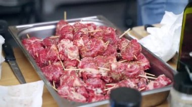 BBC ızgarası için hazırlanmış ahşap çubuklarda tuz, biber ve aroma otlarıyla tatlandırılmış taze sulu et parçaları masada metal şişlerle servis ediliyor. Kızartma için bir yığın çiğ domuz şişi.