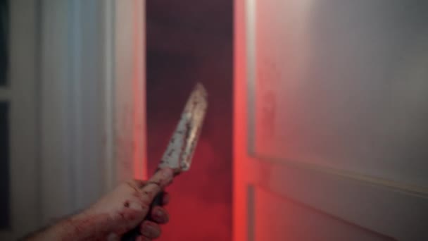 POV primer plano disparo de mano temblorosa criminal sosteniendo cuchillo sangriento después de matar a humanos con crueldad y agresión, asesino en serie entrar en la habitación con la iluminación roja persiguiendo a la víctima. Criminal con — Vídeo de stock