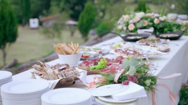 Красиво прикрашений бенкетний стіл зі свіжими квітами букети і різноманітність їжі на тарілках і дерев'яних дошках, підготовка фуршетного столу для офіційної церемонії відкритий, розкішний святкування вечірка — стокове відео
