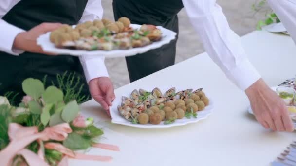 Accoglienza ufficiale di banchetti di lusso con tavoli da banchetto splendidamente decorati, camerieri del ristorante che mettono cibo di lusso sul tavolo per gli ospiti invitati. Piastre bianche e vassoi d'argento con varietà di — Video Stock