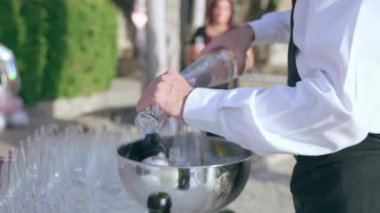 Açık havada resmi parti kutlaması, ziyafet partisinde zarif konuklar, yemek masasında insanlara servis yapan garson. Hizmetçi, orta yaşlı bir kadın için bardağa su dolduruyor. İçecekler dökülüyor.