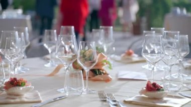 Lüks restoranda resmi bir iş toplantısı, açık havada özel yemek servisi, kristal kadehler, gümüş takımlar, moda yer tutucular ve harika dekore edilmiş yuvarlak masalar.