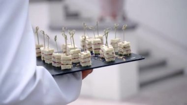 Beyaz üniformalı restoran garsonunun elinde davetliler için nefis atıştırmalıklar, üst düzey restoran mutfağının özel menüsüne sahip hizmetçi toplantıları var. Prosciutto ve salamlı ekmek dilimleri