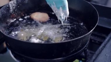 Lüks ziyafet partisi için özel açık hava yemek servisi. Eldivenli profesyonel aşçı. Meyve ve sebzeleri sıvı hamur ile ıslatıp siyah tavada kızgın yağın içine atıyor.