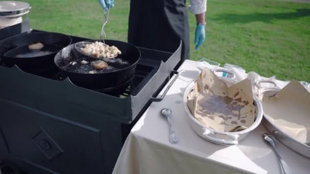 豪華な正式なパーティーのための特別な軽食や前菜と屋外バンケットテーブルを準備プロのレストランシェフ、フライパンフルーツの過程で調理アイテムを使用して制服や手袋でウェイター — ストック動画