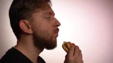 Modern toplumda aşırı kilolu olmanın yaygın sorunu, fast-food restoranından sağlıksız bir burgerin tadına bakan genç adam. Yemek cezbedici, yemek endüstrisini yemeye hazır.