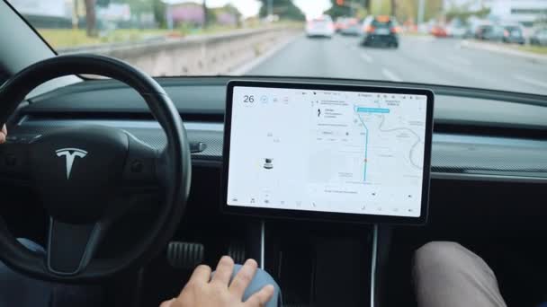 ROMA, ITALIA - 28 DE ABRIL DE 2021: Hombre conduciendo en piloto automático en el innovador coche Tesla eléctrico enchufable, conductor sosteniendo el volante, ajuste de la función de auto-conducción en el monitor de pantalla táctil LCD y conducción — Vídeos de Stock