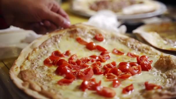 ピザ屋でジューシーなホットラウンドピザとホワイトプレートを好転させる人,カット新鮮なトマトとイタリアのピザ,コショウと溶融モッツァレラチーズ.自家製ピザで有名なマルゲリータ焼き — ストック動画