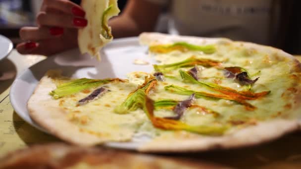 Close up shot of delicious crusty pizza cut on white plate in pizzeria, traditional juicy pizza dough with courgette flowers, salted fish, pepper and melted cheese baked in homemade oven. Italian — Stock Video