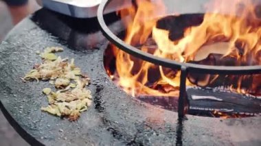 Top view shot of black round bbq smoker with burning fire and grilling chopped onion, traditional barbecue cooking outdoor, process of grilling vegetables for picnic party. High quality 4k footage