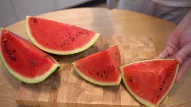 Person cutting ripe watermelon on pieces, juicy red watermelon full of vitamins ready for eating. Rich on minerals and vitamins fruits for healthcare, sweet watermelon dessert. High quality 4k footage