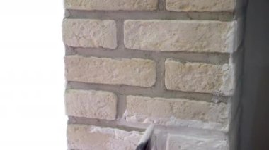 Builder using paintbrush for colouring decorative stone walls surface, man renovating interior walls painting with white colour. Home renovation, construction site. High quality 4k footage