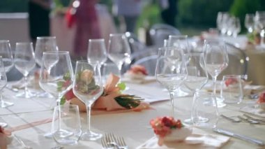 Elegant round table setting in luxury restaurant in the open air, round tables with crystal goblets, exclusive silverware, trendy placeholders and charming flowers bouquets in the middle of the table