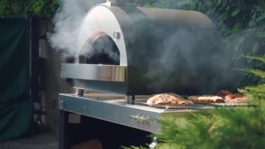 BBQ smoker with long chimney tube and rising smoke outdoor, firing up smoker for roasting food on barbecue grill inside. Process of preparation for picnic party, barbecue cookout. High quality 4k