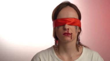 Terrified woman with red ribbon on eyes, bruise and blooding nose, another victim of discrimination, cruelty and abuse. Aggression and torture against innocent female, fear and depression of violence