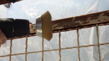 İnşaat alanındaki ağır onarımlar, paslanmış yüzeyi ve elektrikli öğütücüdeki yuvarlak metal fırça başlığını kaldırıyor. Çelik yüzeyi bir açıyla öğüten inşaatçı paslanmış katmanı kaldırıyor.