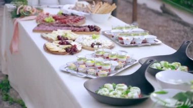 Çıkış partisi için çeşitli özel yemekleri olan uzun bir ziyafet masası içi doldurulmuş atıştırmalıklarla dolu gümüş tepsiler, dilimlenmiş peynir ve et dilimleri ile ahşap tahtalar, ekmek çubukları ile beyaz kaseler. Lüks.