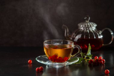 Şeffaf bir fincanda dikenli sıcak çay ve koyu arkaplanda çay..