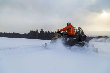 Güney Urallar 'ın dağlarındaki kış ormanlarında hareket eden bir kar aracının atleti..