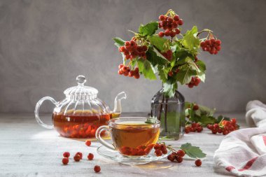 Şeffaf bir fincanda dikenli sıcak çay ve arka planda çay olan çaydanlık..