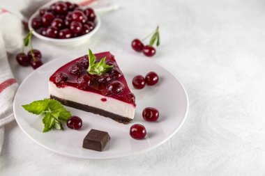 Beyaz bir masada bir tabak kirazlı cheesecake..