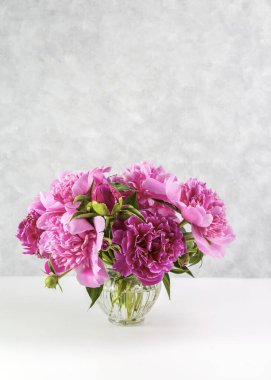 Beyaz masadaki vazoda pembe şakayık demeti. Hediye Sevgililer Günü.