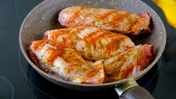 Las alas de pavo se fríen en una sartén en una estufa eléctrica negra y se riegan con aceite vegetal. — Vídeos de Stock