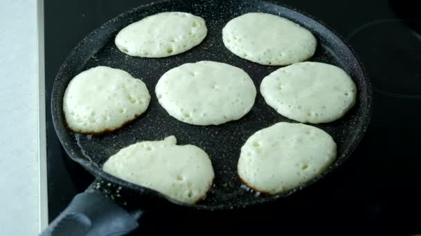 Los buñuelos se fríen en una sartén en una estufa eléctrica negra. — Vídeo de stock