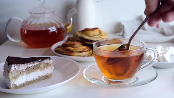 La mano revuelve una cucharadita de azúcar en una taza. Desayuno con pastel. — Vídeos de Stock