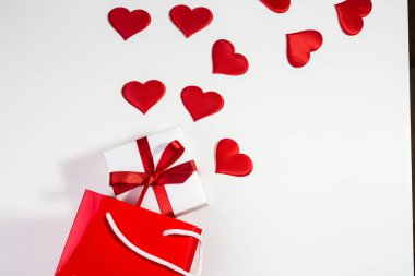 Kırmızı kalpli sevgililer günü geçmişi ve kırmızı çantalı bir hediye. Düz metin kopyalama alanı. 