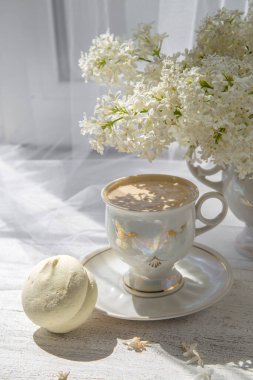 Bir buket beyaz leylak ve cam kenarında şarap olan bir bardak..