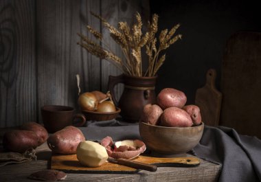 Bir kasede çiğ patates ve ahşap bir masada kesilmiş patates..