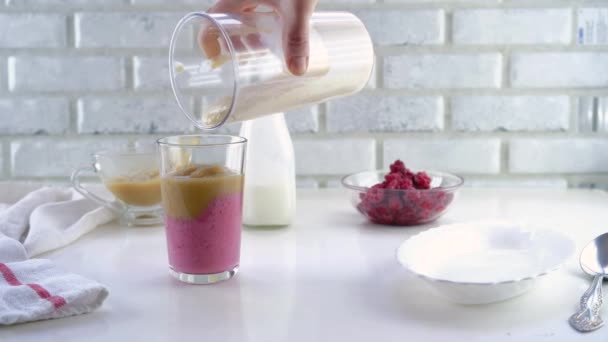 Delicious layered yogurt dessert with applesauce, raspberries and banana. Step-by-step instruction. Step 7. Pour the banana-yogurt mixture into a glass — Stock Video