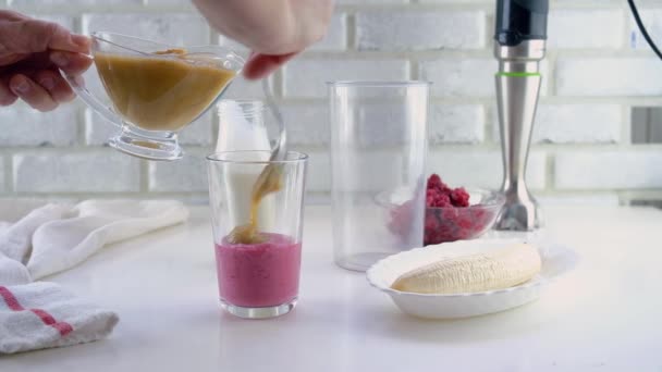 Läckra lager yoghurt dessert med äppelmos, hallon och banan. Steg-för-steg-instruktioner. Steg 4. Applicera ett andra lager äppelmos — Stockvideo