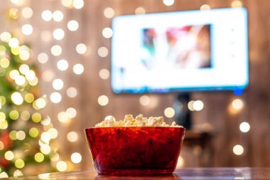 Televizyon ve Noel ağacının arka planında patlamış mısır olan kırmızı kase.